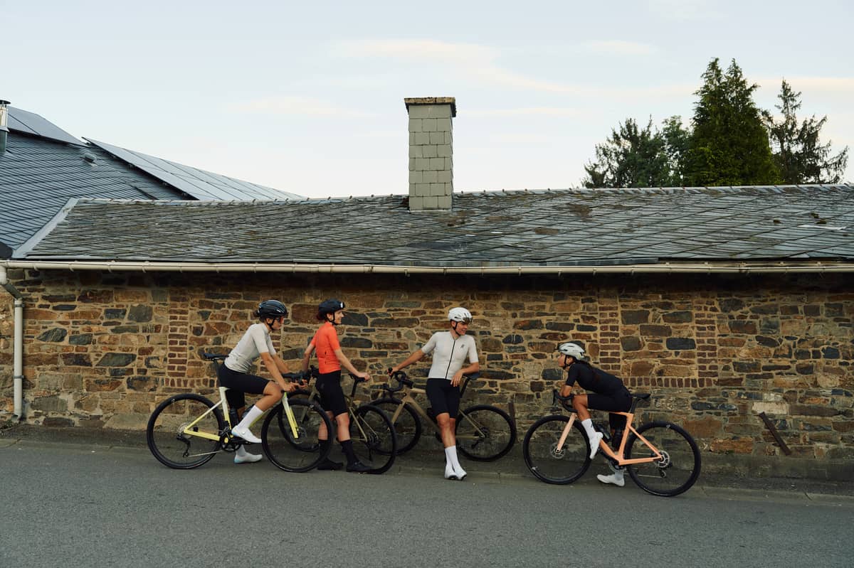 Rose Rennrad leasen: mehrere Fahrradfahrer machen Pause vor Hauswand