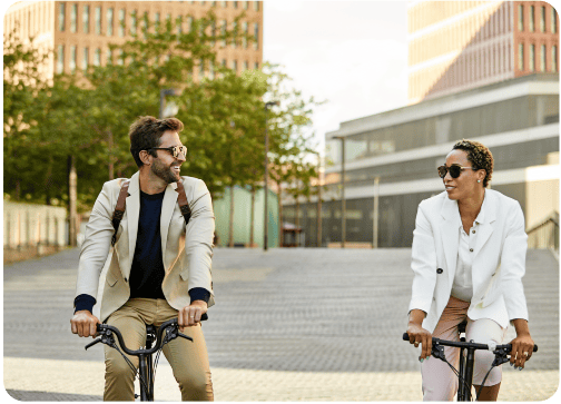 Smiling couple on company bikes in urban surrounding looking at each other