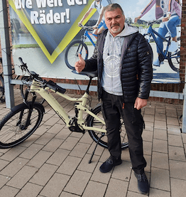 man standing in front of company bike with thumps up