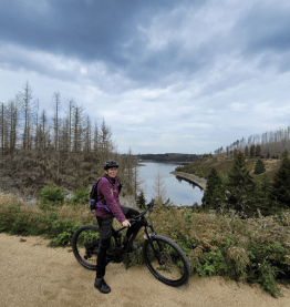 woman with bike smiling towards camera in front of landscape bike leasing