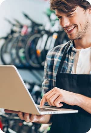 Fahrradhändler grinsendes Gesicht mit Laptop in der Hand