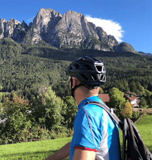 man with helmet and backpack in mountains looking away