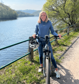 Frau auf Dienstrad stehend vor Gewässer Bikeleasing