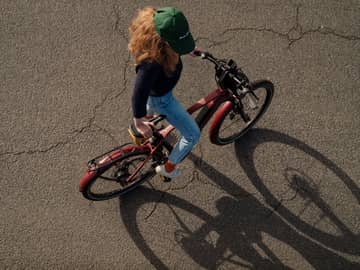 Lease a Bike Frau mit Cap steigt auf rotes E-Bike