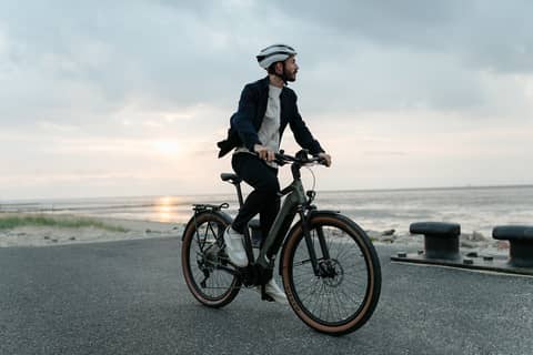 Man on company bike near beach looking away