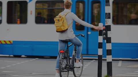 Man with backpack is waiting at traffic lights while tram is passing