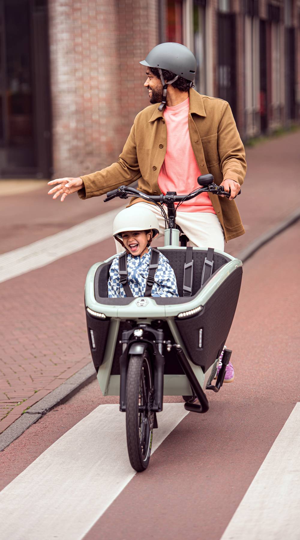 Father rides through the city with a child on a cargo bike