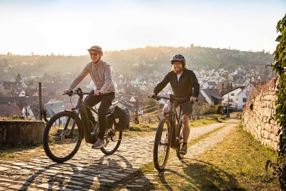 two bikers on Focus bikes riding uphill with city in background