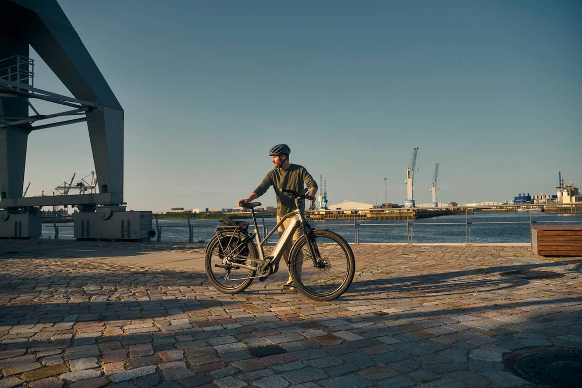 sustainable mobility man standing with bike in front of harbour