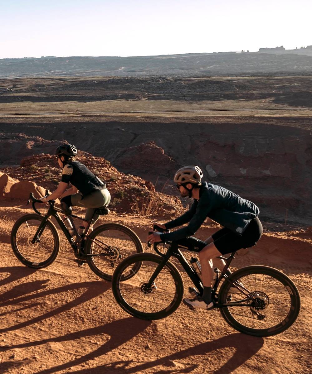 Two cyclists on gravel bikes on a sandy track