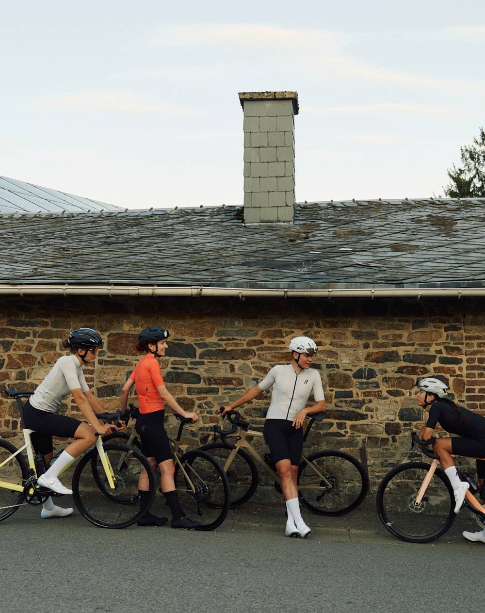 Rose Rennrad leasen: mehrere Fahrradfahrer machen Pause vor Hauswand