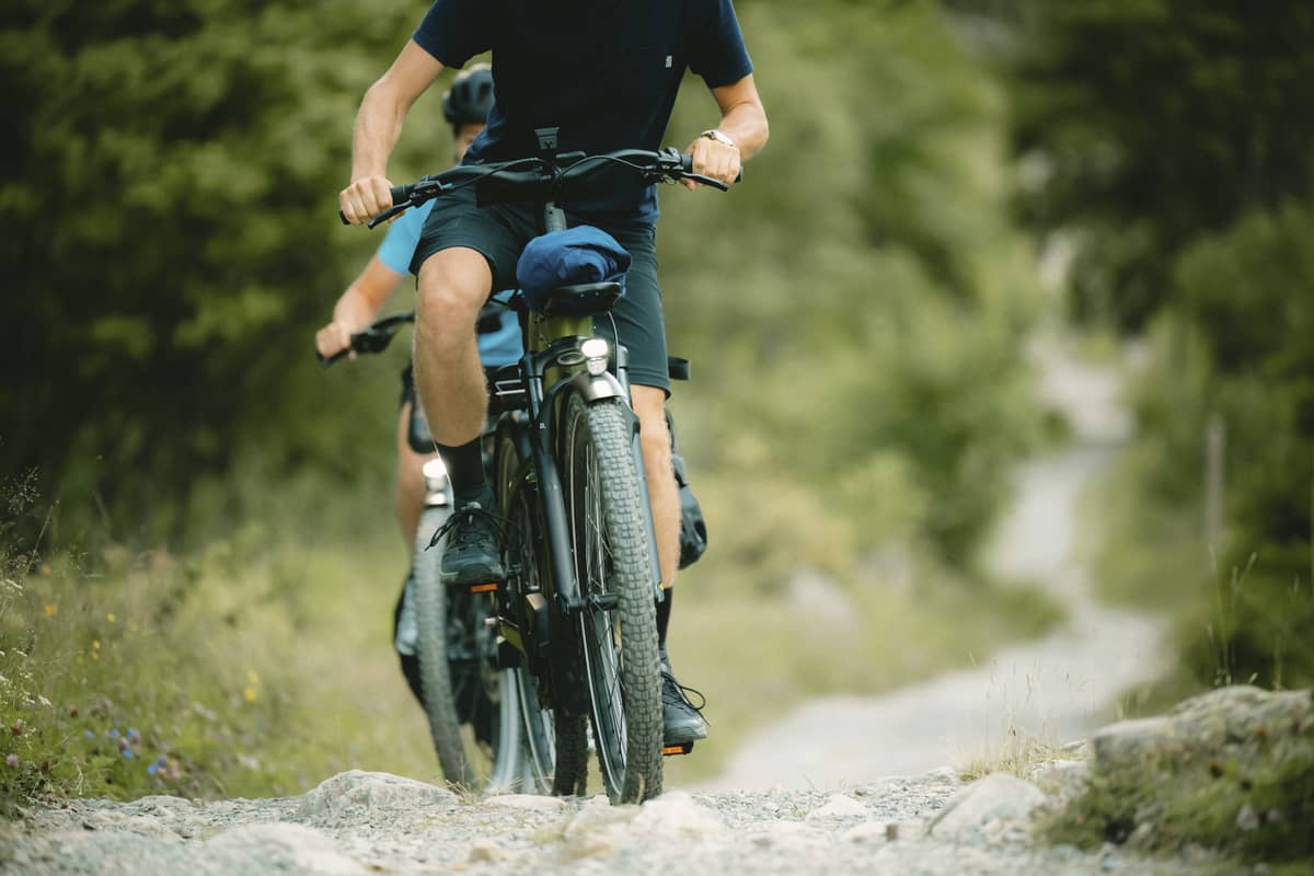 Cyclists on Cannondale bikes riding one after the other on a rocky path