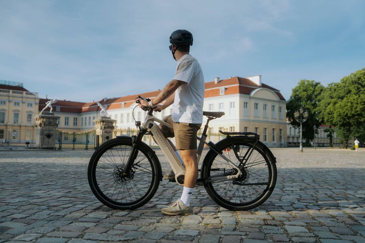 Kalkhoff Mann steht mit Bike vor Gebäude
