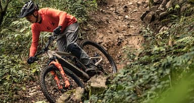 man on mountainbike riding his bike down the hill in forest