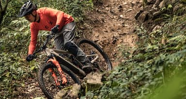 man on mountainbike riding his bike down the hill in forest