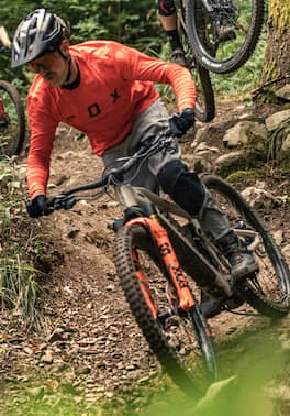 Mountainbiker fährt mit Fahrrad im Wald den Berg hinab