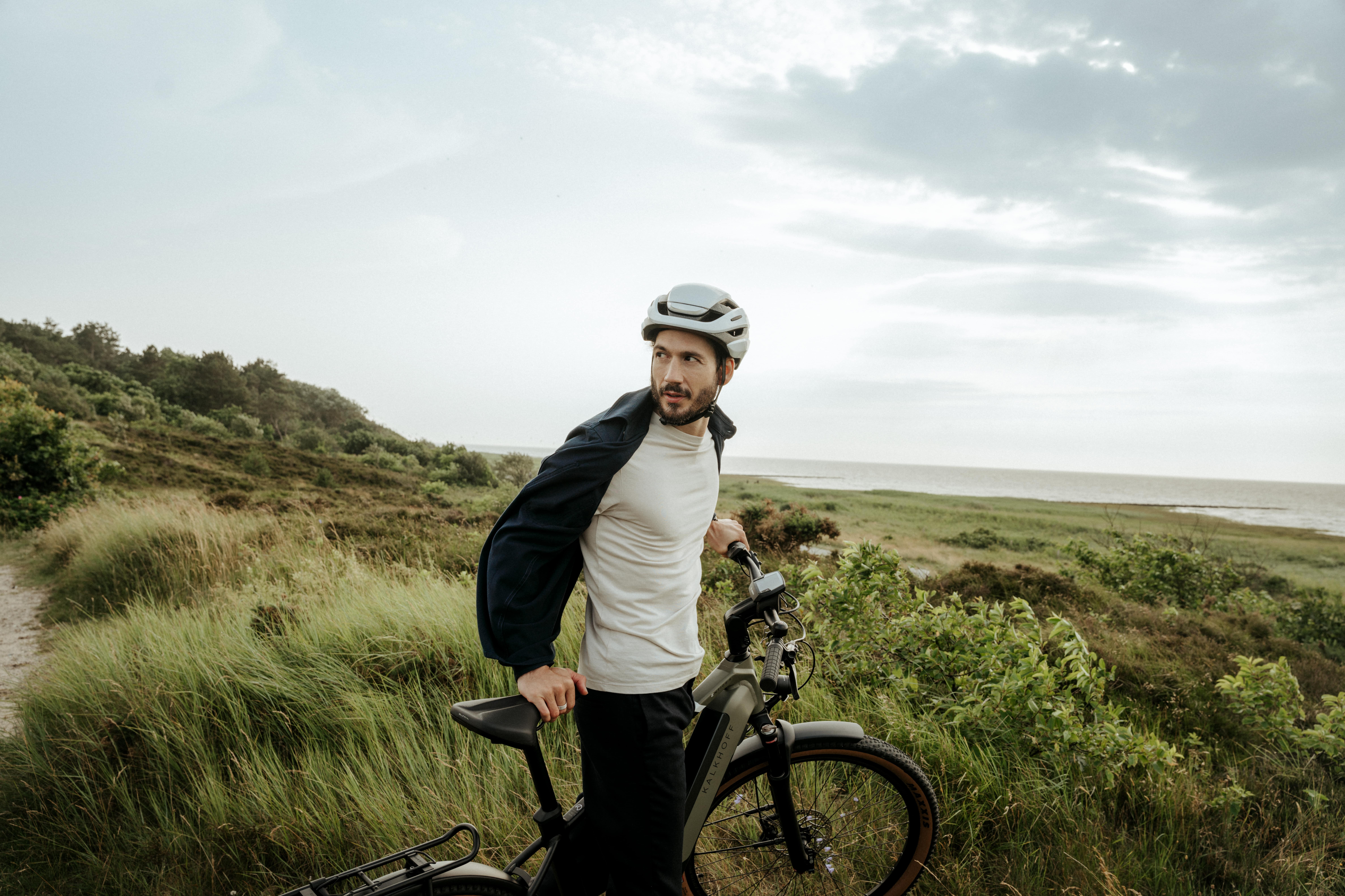 Mann mit Fahrrad in Dünenlandschaft blickt zurück