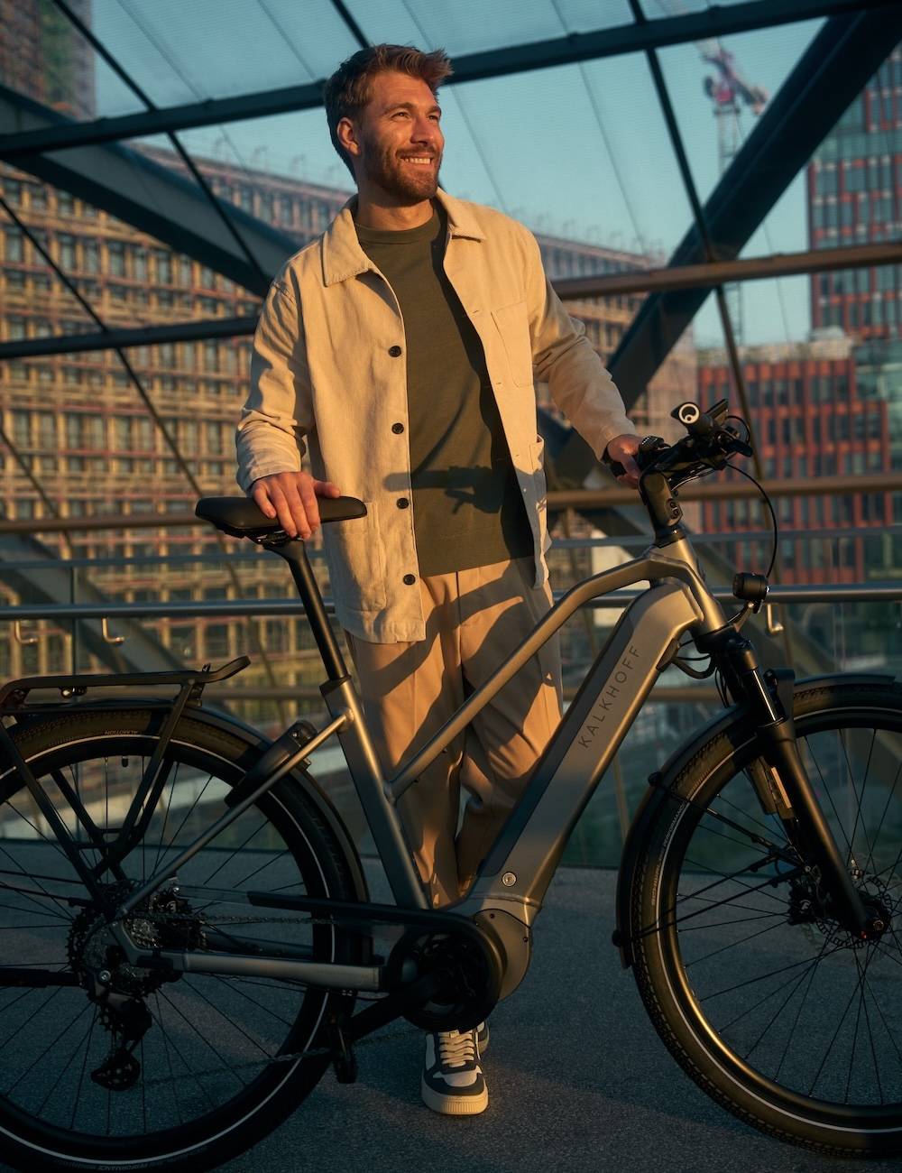 Mann steht mit seinem E-Bike in vor Glasfront