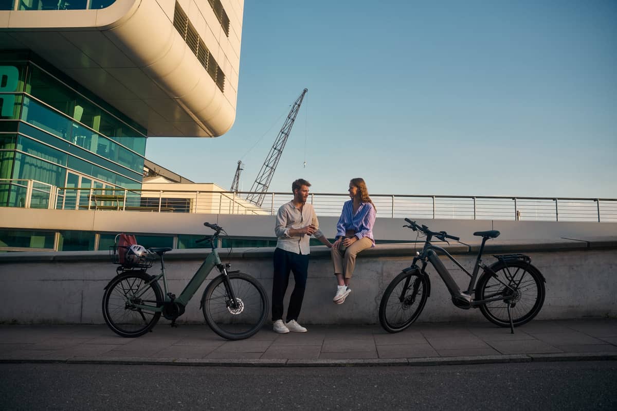 two people sitting on wall with bikes standing next to them