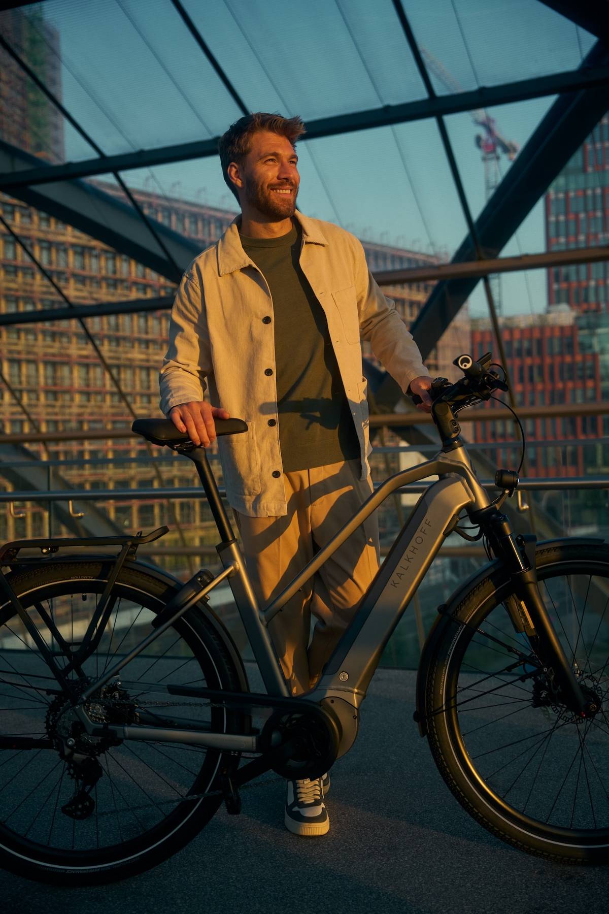 man standing next to bike and smiling while sun is going down