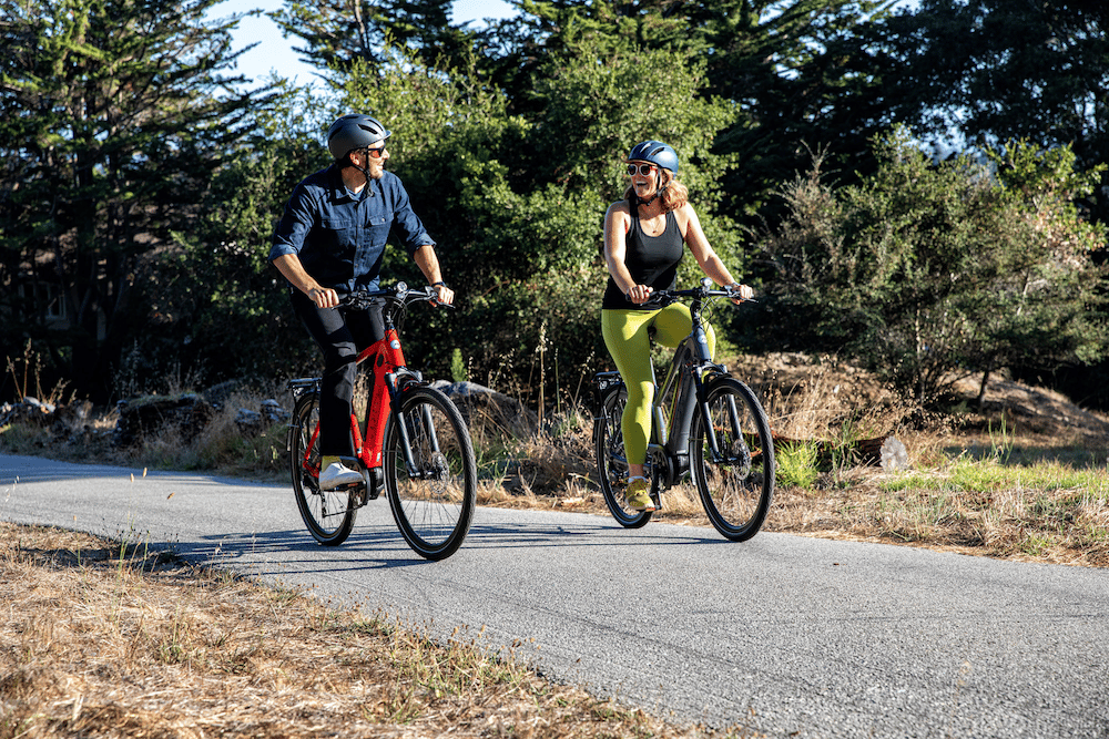 two people riding bike on bike path in summer