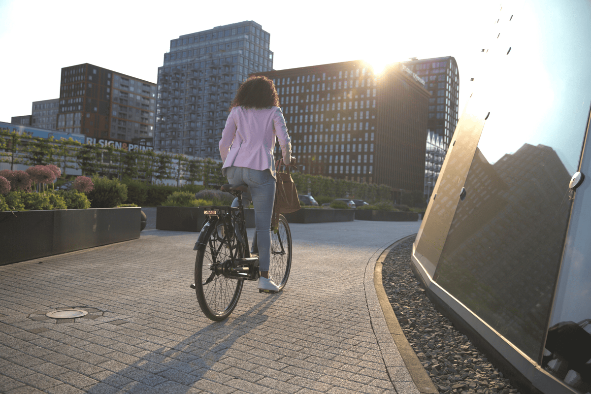 Frau sieht man von hinten und fährt mit Rad Richtung Stadt Skyline