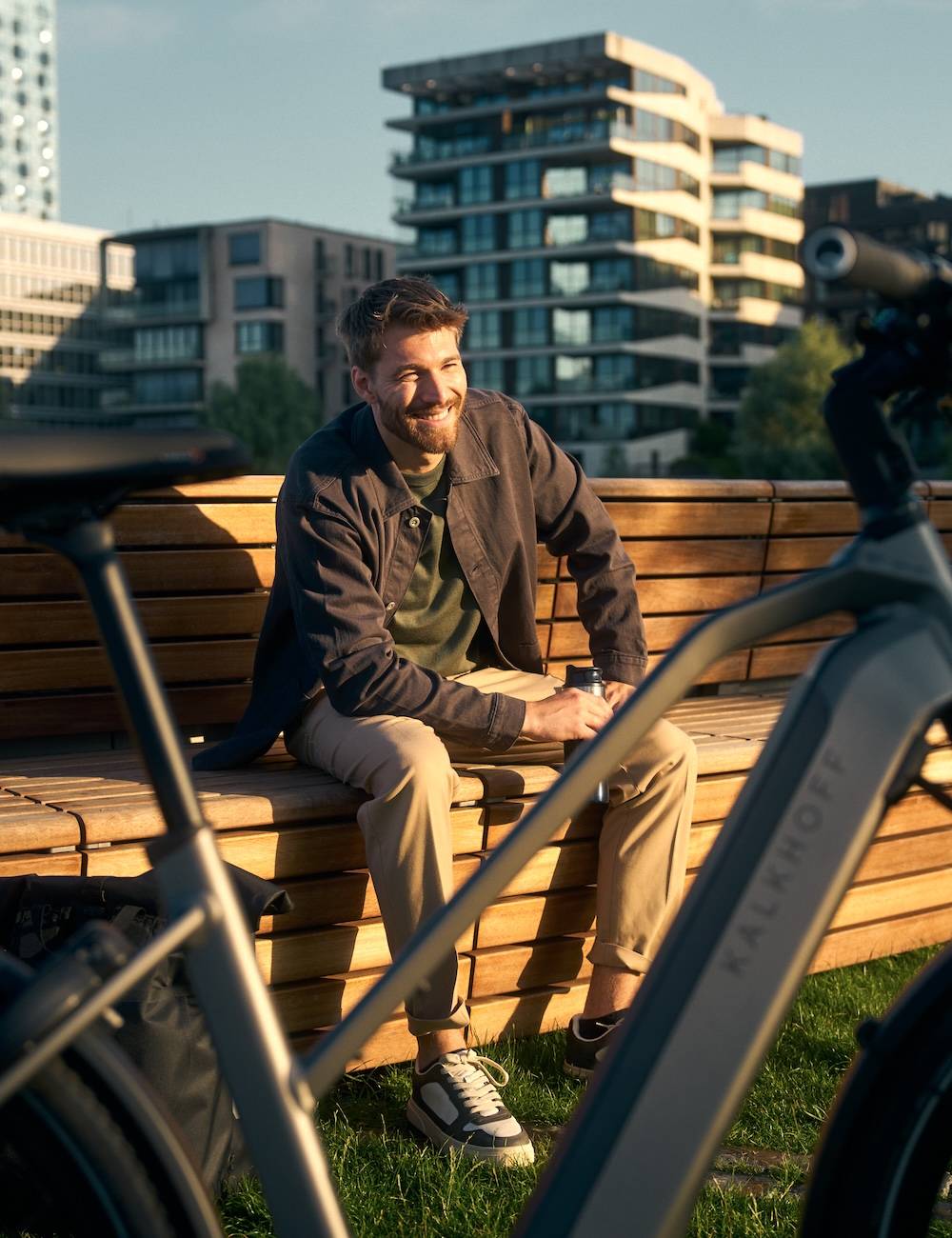 Mann sitzt auf Holzbank hinter seinem E-Bike