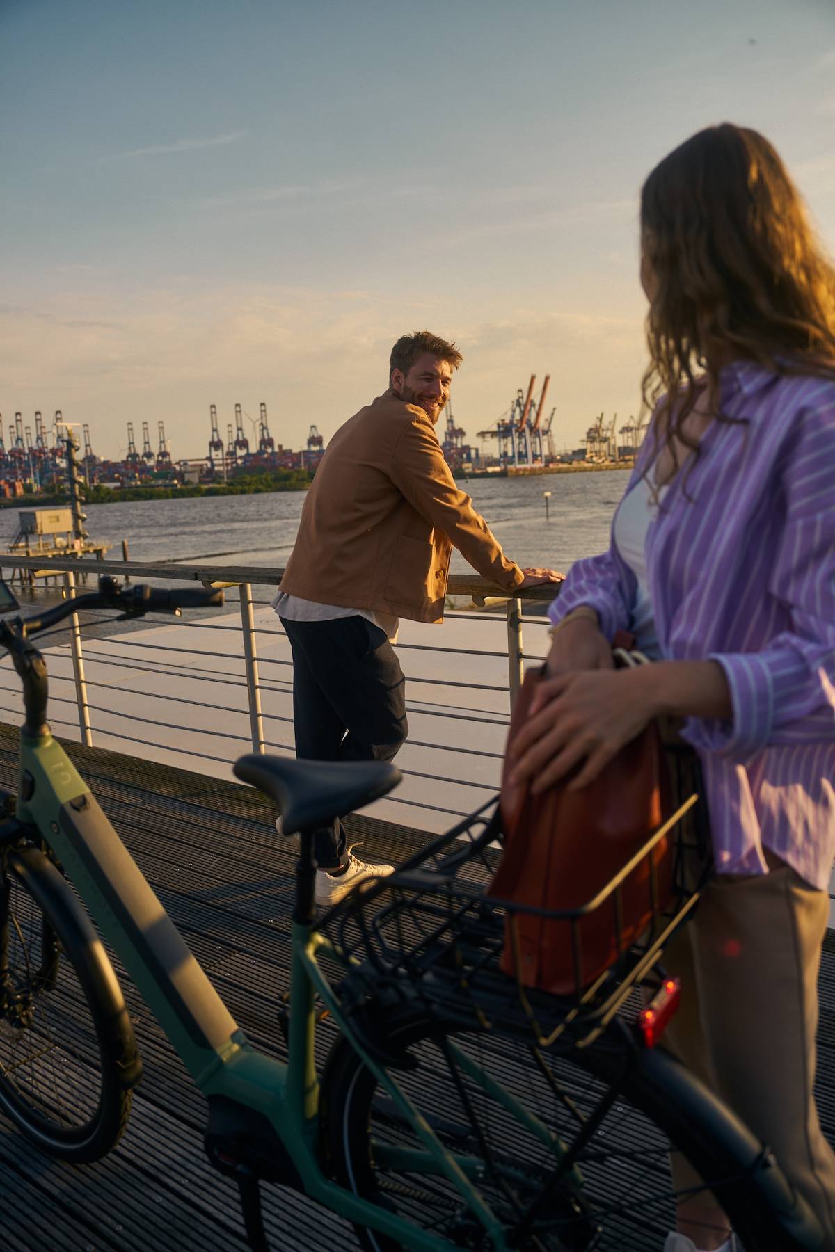 Frau und Mann neben Kalkhoff Firmenfahrrad Leasing stehen vor Hafenkulisse und schauen sich an