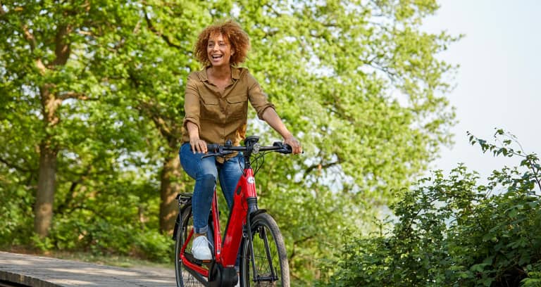 Woman on red Gazelle bike laughing and riding bike in nature